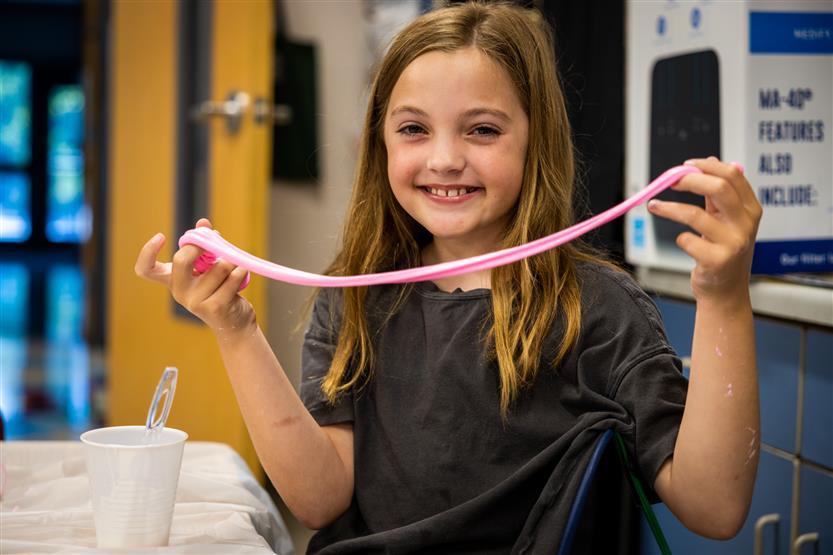 A girl with brown hair holds up slime